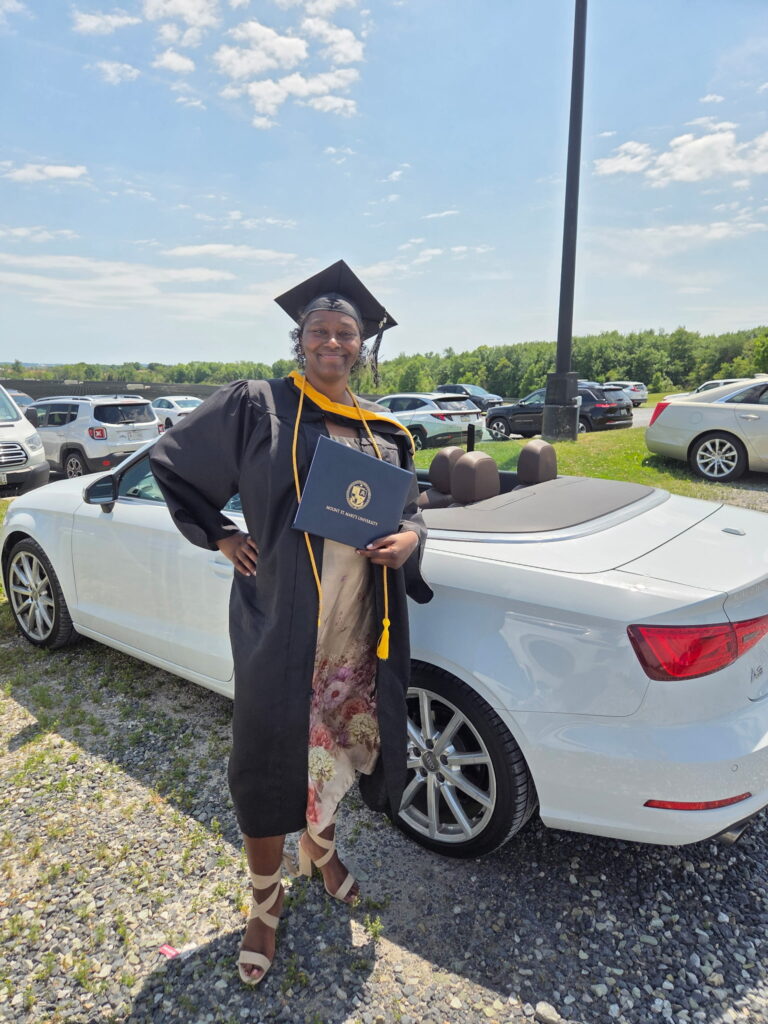 Liver recipient Talisha stands next to a car in her cap and gown after graduating from Mount St. Mary University with a Bachelor of Science degree.