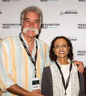 Two smiling attendees pose for a photo at the Washington West Film Festival, wearing lanyards with badges.