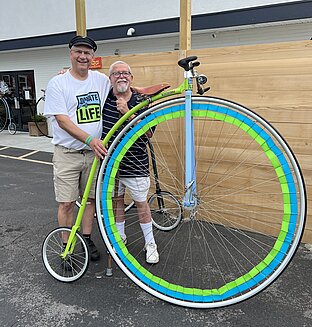 Bill Soloway, heart transplant recipient stands with his donors father and his Donate Life high wheel bicycle.