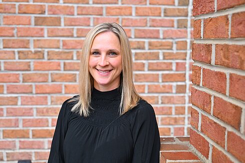 Director, Donor Services Center, Catherine LoVerdi, stands in front of Infinite Legacy's office smiling.