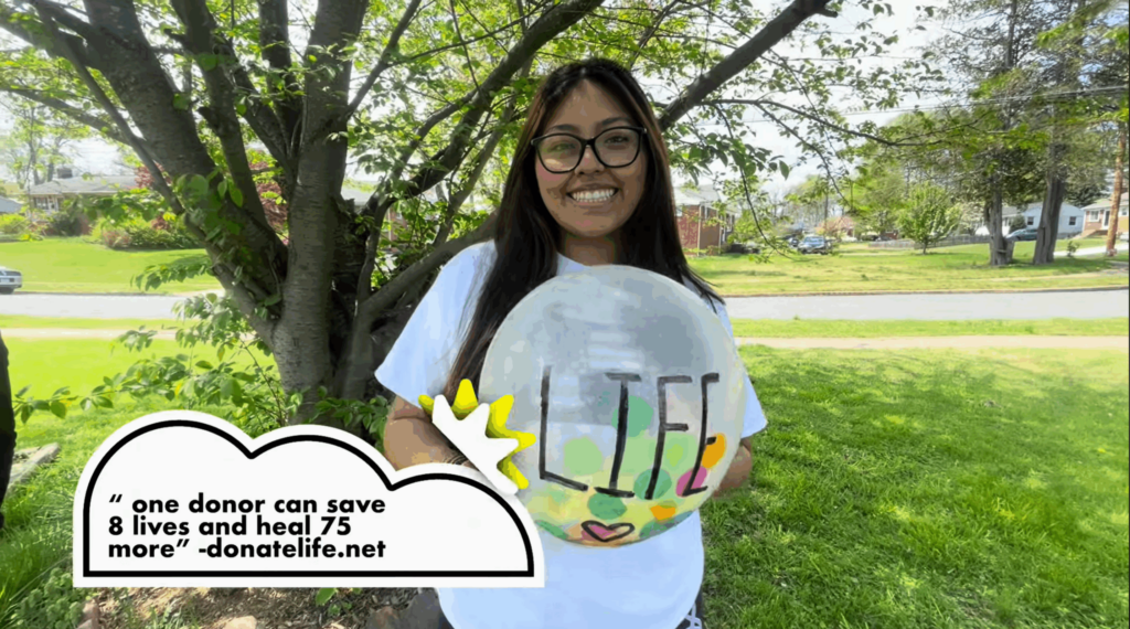 A student smiles while holding a Life balloon as apart of her submission to one of Infinite Legacy's scholarship.