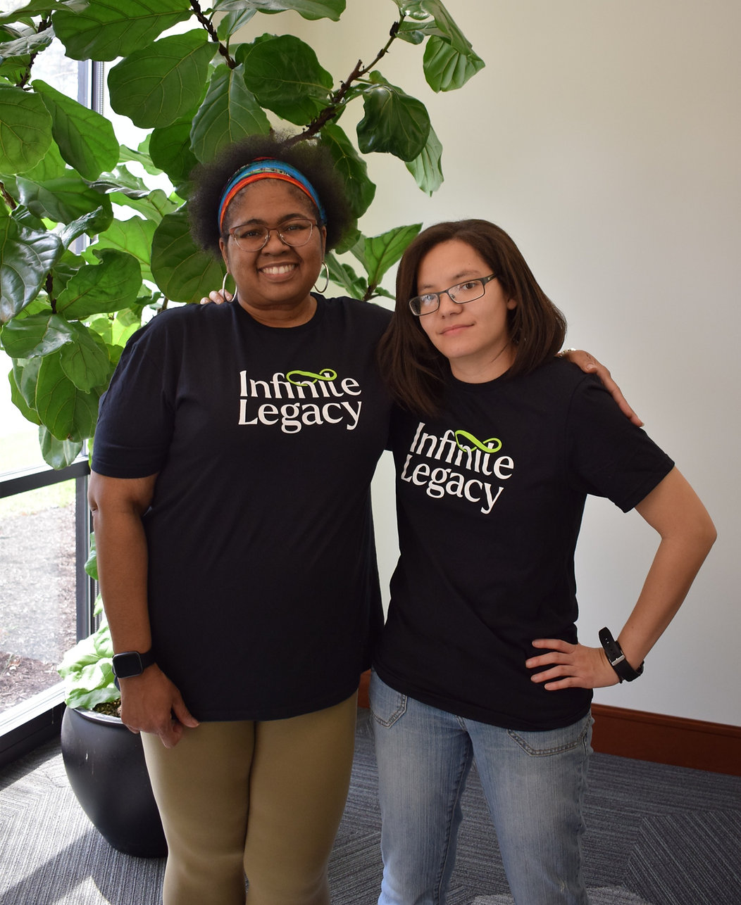 Two Infinite Legacy staff members wear Infinite Legacy t shirts.