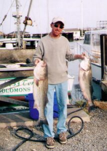 Donor hero Charles holds two large fish he caught.