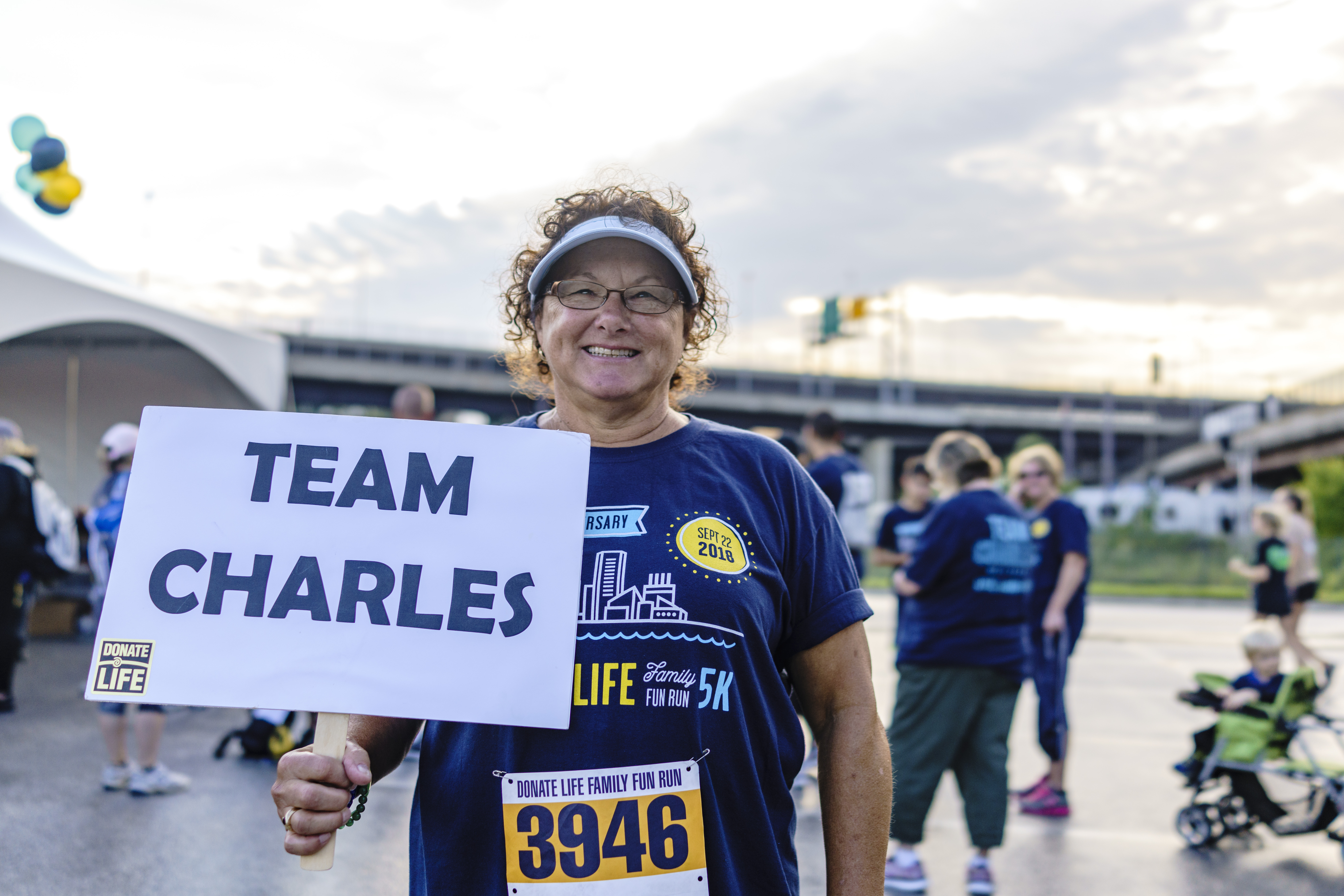 Jeannette smiles while she holds a Team Charles sign to honor her son at the annual Donate Life Family Fun Run.