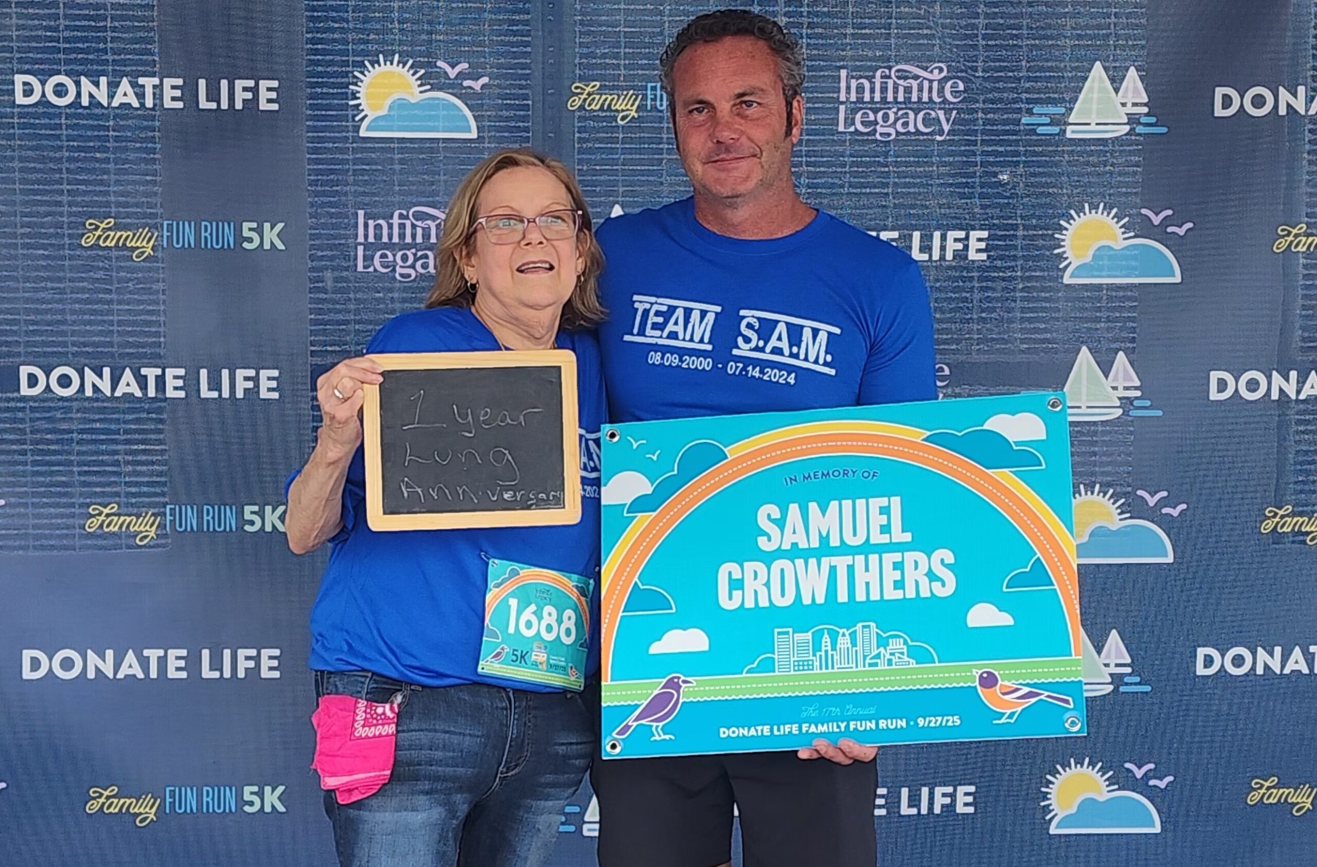 Proud donor dad Dave Crowthers holds an In Memory of Sam Crowthers sign with his son's right lung recipient, Stacy Nygaard, at the 2025 Donate Life Family Fun Run.