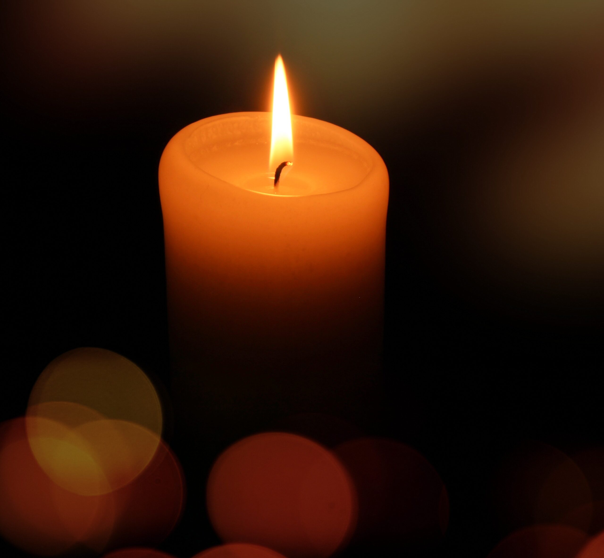 Close-up of a lit candle representing remembrance and the lasting legacy of a loved one.